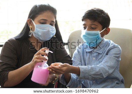 Mother pouring handwash sanitizer on palm of her son Royalty-Free Stock Photo #1698470962