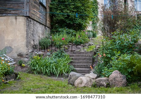Staircase in the garden with flowers and collected stones over green nature background. View of backyard. Nobody. Countryside.