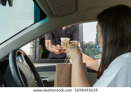 Woman in protective mask taking coffee at drive thru during coronavirus outbreak Royalty-Free Stock Photo #1698492634