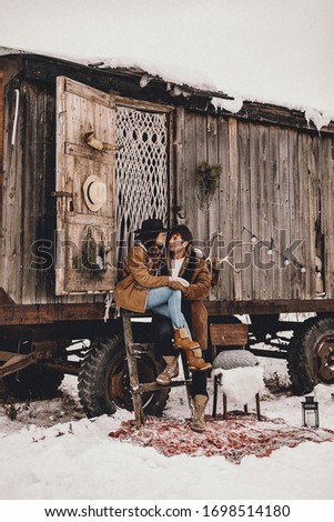 Loving couple next to wooden van at a ranch in Canada, in winter western. NOISE EFFECT ON PHOTOS