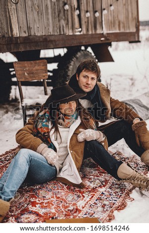 Loving couple next to wooden van at a ranch in Canada, in winter western. NOISE EFFECT ON PHOTOS
