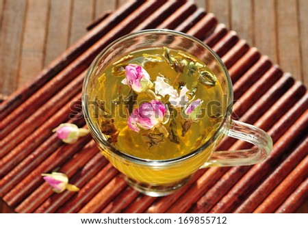 Glass cup with fresh green tea and dry roses 