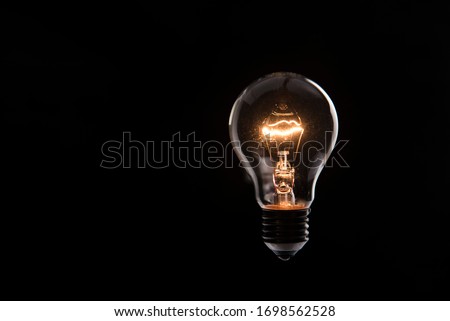 tungsten light bulb lit on black background Royalty-Free Stock Photo #1698562528
