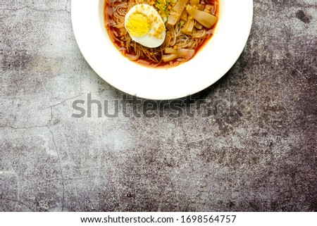 A flatlay half picture of one rare traditional food from Malaysia call "mee belacan" on copy space crack floor. A noodle eat together with squid and shrimp paste soup.