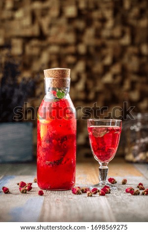 Side view on fresh cool orange berry lemonade with mint on the wooden table, vertical