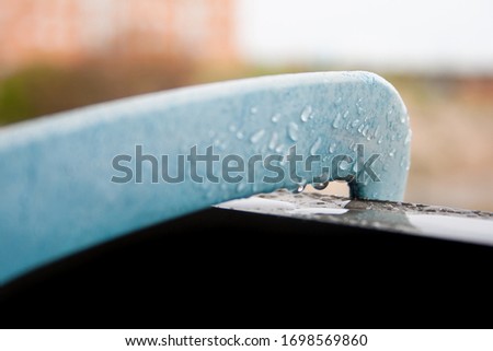 Plastic piece with water drops on the railing of a wet valcon during a rainy day