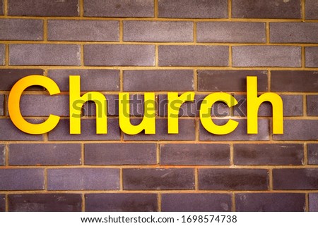 Sign reading Church in large, bold yellow capital letters on a brick wall
