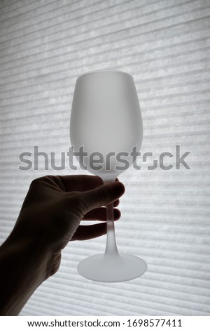 
glass in hand on a background of blinds