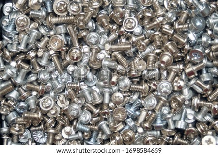 Gray texture background of many randomly scattered computer screws