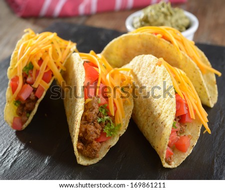Tacos with ground beef, cheese, vegetables, and guacamole sauce