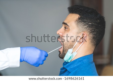Getting Covid-19 Sample from Mouth . Doing Coronavirus Test to an Young Man from the Saliva. Woman Being Checked at the Hospital.Covid-19 Concept. Royalty-Free Stock Photo #1698626161