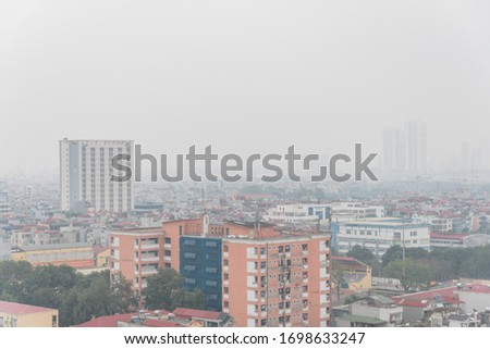 Aerial view polluted air in the East of Hanoi, Vietnam. Foggy urban sprawl with mix of high-rise building, condominium, residential houses and skyscraper under construction.