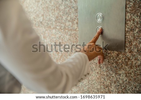 Human hand pressing the last floor button in the elevator. Person pushing down arrow elevator button. Businessman pressing on elevator button, waiting door open to enter inside the lift.