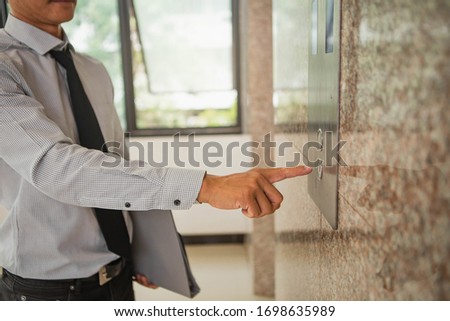 Human hand pressing the last floor button in the elevator. Person pushing down arrow elevator button. Businessman pressing on elevator button, waiting door open to enter inside the lift.