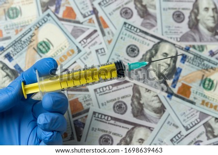 doctors or nurse hand holding syringe on money background. expensive treatment concept.