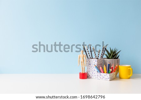Student creative desk with colorful office supplies and blue wall background. Back to school.