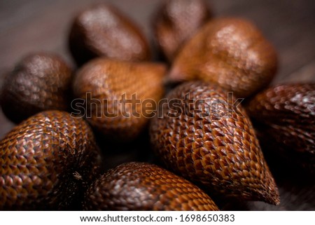 Exotic tropical salak fruit also known as snake fruit. Close-up shot of the snake fruit on a wooden brown background.