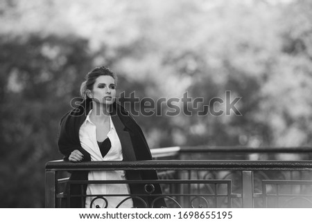 Beautiful lonely woman with hair developing in the wind and full lips on the bridge on a cold gray day. Black and white art photo. Soft selective focus.