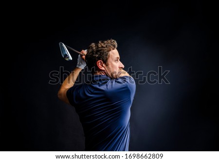 Hitting the perfect golf shot. Golf player golfing in studio isolated on dark background