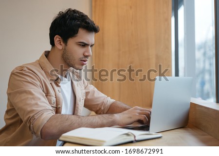 Successful asian business man using laptop computer, typing on keyboard, watching training courses, planning start up in office. Indian freelancer working from home