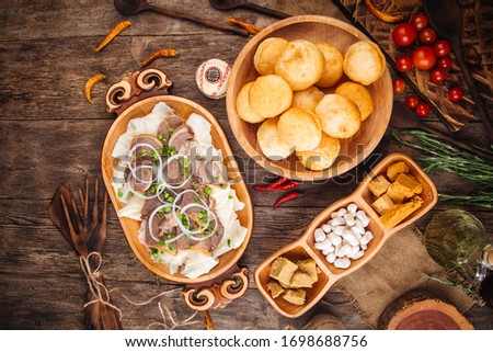 Top view on a traditional national kazakh cuisine dishes beshbarmak with boiled dough and meat in wooden bowl, baursaks fried dough on a wooden table horizontal Royalty-Free Stock Photo #1698688756