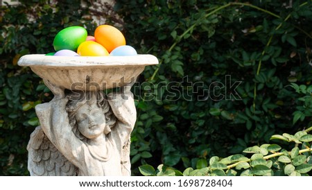 Easter eggs on a statue of a child angel in the garden