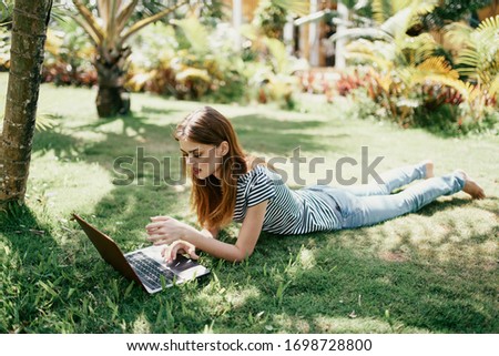 young woman with laptop outdoors with a drink