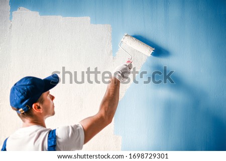 Painter painting a wall with paint roller. Builder worker painting surface with white color. Royalty-Free Stock Photo #1698729301