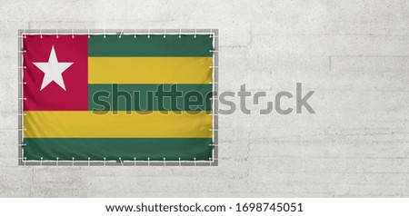 Togo flag on a tarpaulin that is placed on a concrete wall