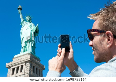 Personal pov perspective of tourist taking picture of the Statue of Liberty with his mobile phone