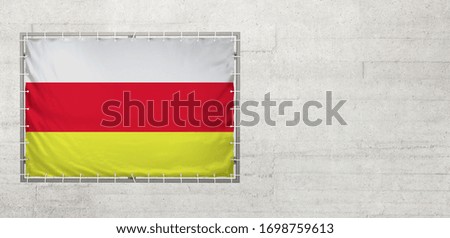 South Ossetia flag on a tarpaulin that is placed on a concrete wall