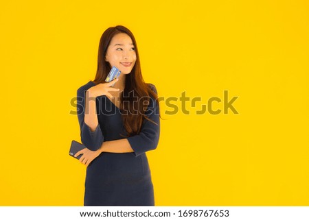 Portrait beautiful young asian woman with smart mobile phone or cell phone and credit card yellow isolated background