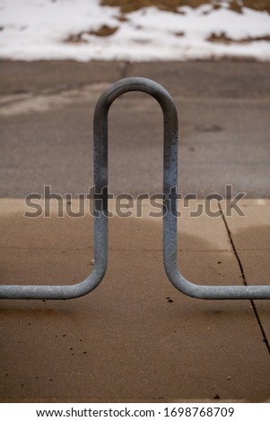 An abstract photo of an urban bike rack on a wet cement sidewalk.