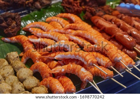 Prawn, meat balls and sausages on sticks in a sheet pan on street food market in Phuket island, Thailand, close up. 