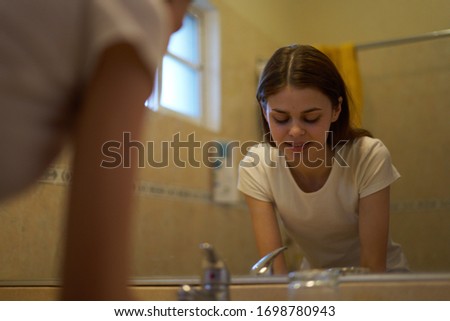 young woman in a white t-shirt looks in the mirror