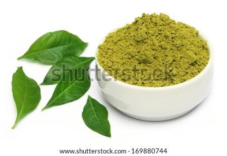 Henna leaves with powder on ceramic bowl over white background