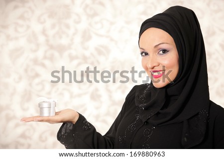 Model dressed in traditional Arabic style, holding present box.