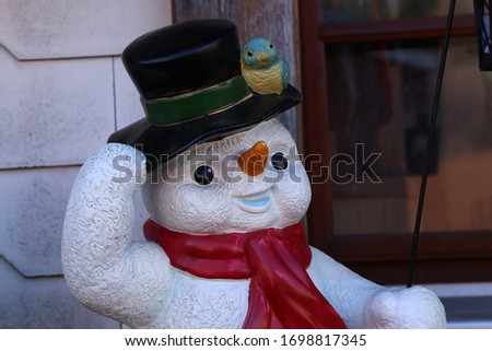Cheerful snowman is standing at the entrance to the house