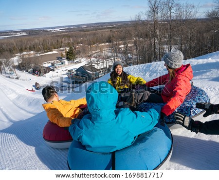 Group of multiracial millenials snow tubing in the winter in Canada with an active lifestyle