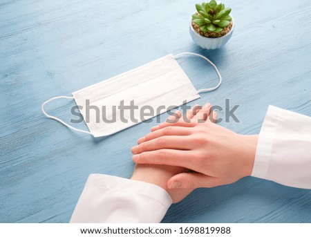 Doctor's hands and a protective mask on a blue table. Doctor with a medical mask at the table.