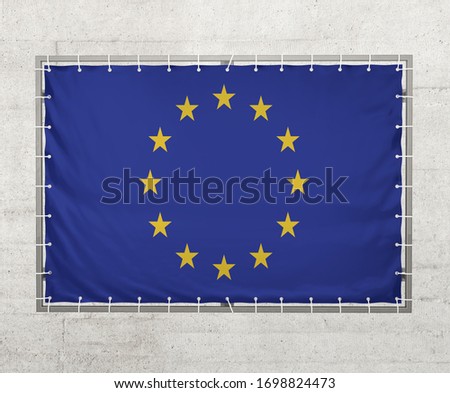  European Union flag on a tarpaulin that is placed on a concrete wall.
