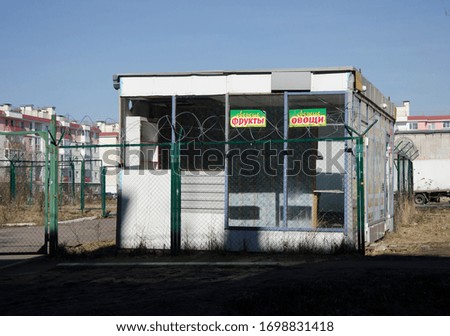 Abandoned street stall  behind the iron wire. Inscription "fresh vegetables and fruits".