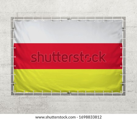 North Ossetia flag on a tarpaulin that is placed on a concrete wall