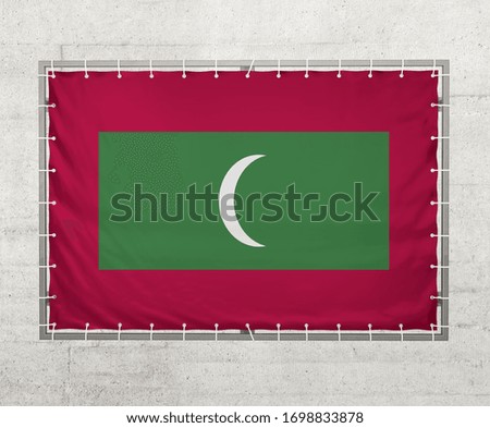 Maldives  flag on a tarpaulin that is placed on a concrete wall