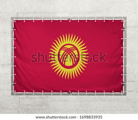Kyrgyzstan  flag on a tarpaulin that is placed on a concrete wall
