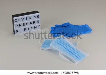 Surgical masks and pair of latex medical gloves. Lightbox with the message “COVID-19. Prepare & Fight”
