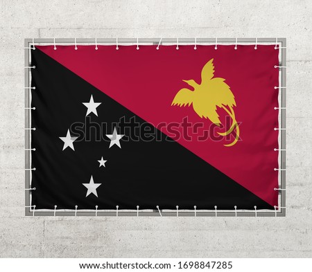 Papua New Guinea flag on a tarpaulin that is placed on a concrete wall