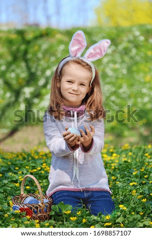 Vertical picture of a girl collecting colored eggs at the egg hunt