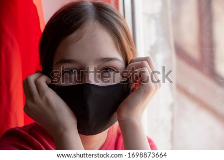 Girl in a medical protective mask. Coronavirus epidemic. Conceptual image. Symbol. Stop the virus. Protective equipment. Girl 9 years old in a medical mask. Virus. Bacteria. Teenager in red clothes