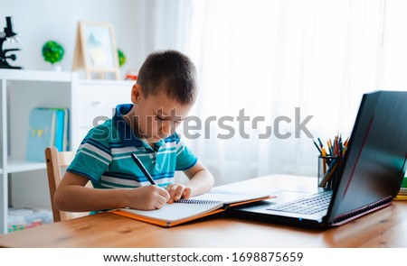 Distance learning online education. A schoolboy boy studies at home and does school homework. A home distance learning. Royalty-Free Stock Photo #1698875659